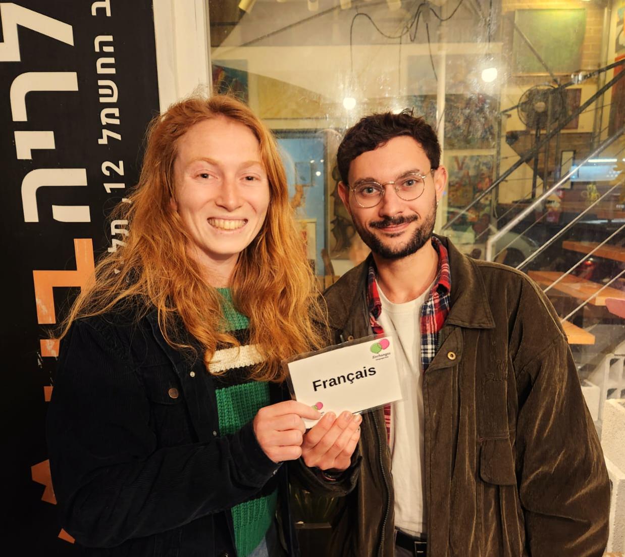 Two people at Tel-A-Lingo holding a table sign for the French language table